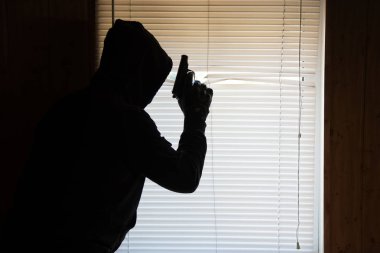 Silahlı riminal pencereden gözetlemektir. Hırsız eve giriyor.