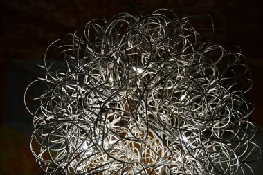 Kavisli dolaşmış teller avize closeup. Gümüş tonları metal tel abajur. Çağdaş iç aydınlatma lambası. Soyut dokulu arka plan. Kavisli çizgiler kaotik desen. Fütüristik bir fon. Geometrik çizgi şekilleri.