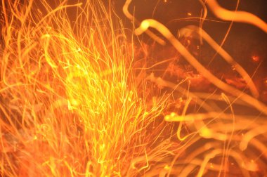 Alev kıvılcımları izleri. Yanan izler karanlık zeminde parlıyor. Soyut ateşli arka plan. Turuncu renk ateş kıvılcımşenlik ateşinden uçuyor. Kopyalama alanı ile doğal desen. Güzel soyut arka plan. Yangın izi yanıyor.