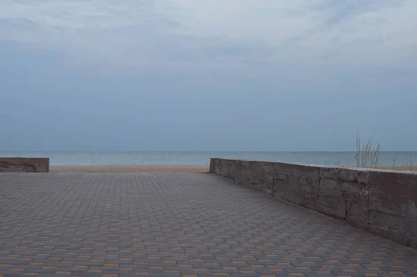 黄昏时分最小的海景的几何概念 没有人和粗糙的水泥边界之间的棋盘瓦走道和沙滩沙与高野生植物 夜空中模糊的月亮 黑海景观 — 图库照片