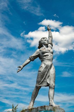 Beyaz bulutlar arka plan ile mavi gökyüzünde güçlü kadın tarihi anıt. Ukrayna'nın Odessa kırsalSosyal gerçekçilik heykel. Sosyal-Gerçekçiliğin Anıtsal Heykelleri. Sovyet kadın heykeli. Yükselen eli yükselen gururlu kadın heykeli 