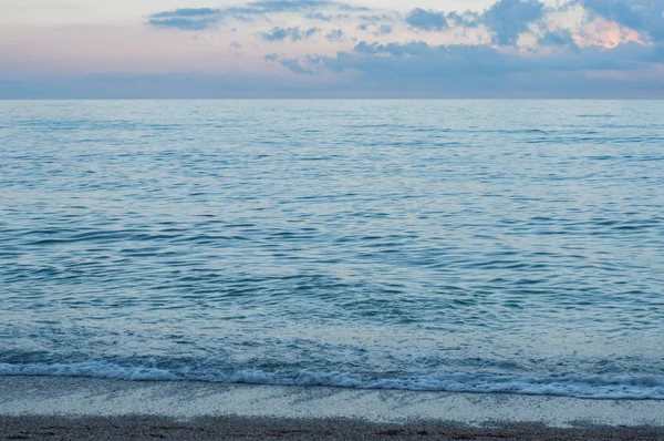 波浪海水在蓝色紫色的黄昏夜晚与风景如画的云景 黑海海岸的海景 摇曳的海潮来到潮湿的沙滩沙上 旅游风景 宁静的海景 暑假放松 — 图库照片