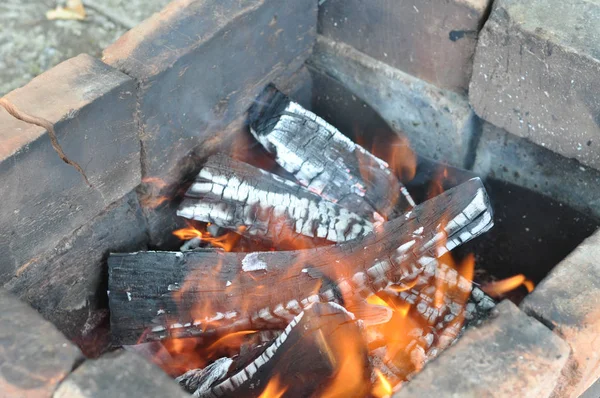 燃烧的柴火与黑色裂开的表面覆盖着白色和灰色的灰烬 陶器烧焦的砖块在旧木炭曼加尔 烧焦的木材原木纹理与火焰 火热的背景 烧烤胸罩内 篝火特写 — 图库照片