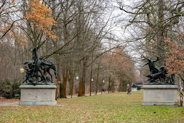 德国柏林蒂尔加滕公园的石基上两座雕塑纪念碑 宁静的景观与无法辨认的夫妇走在秋天的公园草坪与绿草覆盖着干树叶 德国柏林公园 — 图库照片