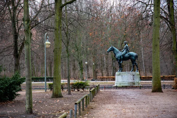 Old monument and rows of trees and retro streetlights in Tiergarten park of Berlin Germany. Tranquil landscape with nobody in autumn season. View to antique bronze sculpture on stone pedestal. Tiergarten park of Berlin Germany. Autumn landscape.
