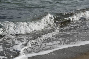 Ukrayna'nın Odessa kentinde Karadeniz'in ıslak kum kıyı şeridi yakınında beyaz köpük ile sıçrama dalgaları. Soğuk deniz suyu. Seascape'te kimse yok. Deniz manzarası.  