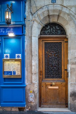 Paris / Fransa - 06 26 2019: Vintage süslü ızgaraları ile yaşlı ahşap kapı. Mavi boyalı ahşap duvar panelleri ile antiktaş bina dış. Paris Fransa Barok mimarisi. Fransız cepheleri.
