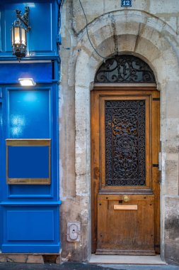 Paris Fransa'da eski binanın antika fener ile mavi boyalı çerçeveli duvar paneli yakınında Yaşlı ahşap kapı. Klasik mimaride antik evin vintage kemer kapı ve yıpranmış taş duvar.