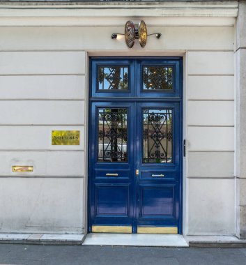 Paris Fransa'da eski binanın güzel antika mavi boyalı kapı. Klasik mimaride eski evin siyah süslü ızgaraları ve sarı metal isim plakaları ile Vintage ahşap kapı.