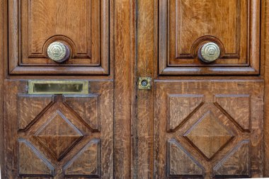 Pirinç kapı toklukları ve Paris Fransa'da yaşlı ahşap kapı hasarlı anahtar deliği. Eşkenar dörtgen desenli ahşap kapı panellerinde posta kutusu yuvası. Çerçeveli kapı panellerinin dokulu ahşap yüzeyi.