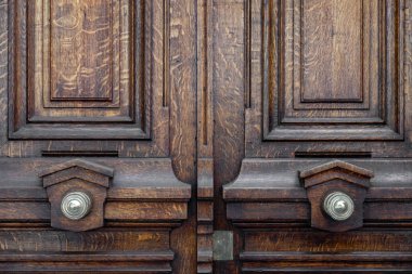 Paris Fransa'da yaşlı ahşap çift kapı Vintage süslü metal kapı tonları. Simetrik kolları ve eski kapı closeup koyu ahşap doku. Kapı panel çerçevelerinin cilalı desenli ahşap yüzeyi.