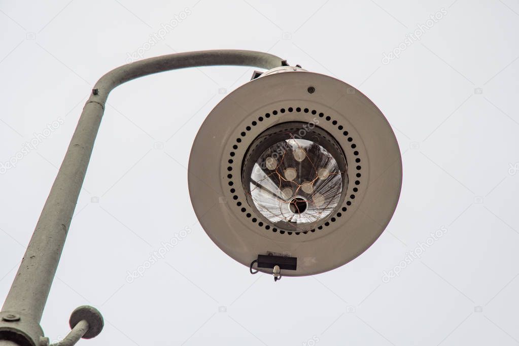 Retro style streetlight closeup on gray background. Round metal lampshade with shiny glass bulb in the center. Outdoor electric lighting equipment. Streetlights in city of Berlin Germany.