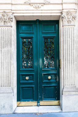 Koyu yeşil renkte boyanmış kapı ile giriş yanları kabartma sütunları ile klasik mimarinin oluşturulması. Paris Fransa'da binanın kapı pencerelerinde süslü ızgaralar ile zarif kapı.