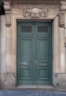 Klasik mimari sütunlar ve ahşap çerçeveli kapı üzerinde taş kabartma süslemeleri pirinç kolları ile yeşil renkte boyanmış. Paris Fransa'da retro binanın dikdörtgen şekil girişi.