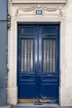 Paris / Fransa - 06 26 2019: Dikey desenli ızgaralarla korunan mat camlı kapı kapı. Koyu mavi eski boyanmış antikkapı ve eski dip kısmı. Avrupa kasabasında antika bina