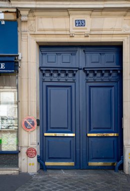Paris / Fransa - 06 26 2019: Avrupa eski kentinde eski binanın zarif lacivert boyalı antika çerçeveli kapı. Mat boyalı ahşap kapı panelleri ve parlak parlak altın metal plakalar. Vintage kapı. Avrupa'da retro bina girişi.