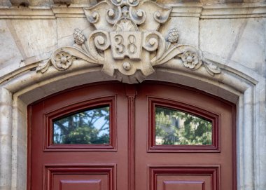 Heykel volute ve kabartma taş elemanları cam pencereler ile eski kahverengi ahşap kapının üst üstünde. Antika süslü kapı kemeri. Paris Fransa'da bina mimari detayları. Vintage dokular