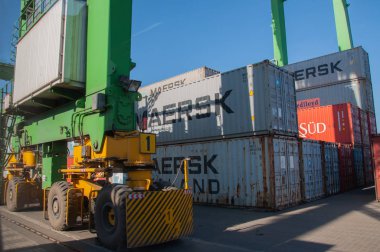 Ağır lastiklerle dolu köprünün altında paslı metal konteynırlar Maersk. TIS Grubu kuru kargo limanının konteyner terminali. Maersk konteynırları konteynır yükleme makinesinin altında ve kocaman lastikleri var. Deniz limanının sanayi manzarası. Odessa, Ukrayna, 10 12 2018