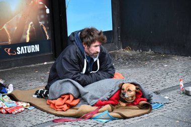 Berlin / Almanya - 12 09 2019: Evsiz fakir adam battaniyeyle örtülü köpekle yerde oturuyor, Berlin, Almanya Avrupa. 
