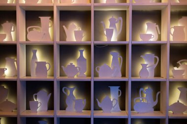 Mutfak aletlerinin çeşitli şekillerinde dolap rafları. Çaydanlık, fincan, süt sürahisi ve beyaz mor arka ışıklandırmalı şeker kasesi siluetleri. Kahve molası