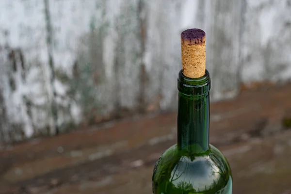 ダークパープルの赤ワインで染色されたコルク栓で閉じられたワインのボトルネックの上 緑のガラス瓶の上にコピースペース付きの木の背景 — ストック写真