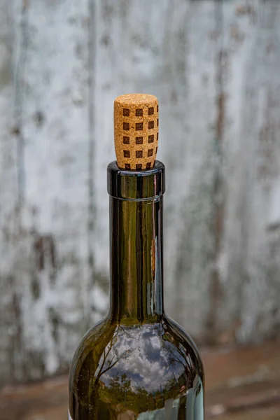 在光滑的绿色玻璃瓶白葡萄酒中的水泡倒映物 瓶塞上有方形点缀的瓶塞 瓶盖在破旧的木头背景上 普罗旺斯葡萄园依旧生机勃勃 — 图库照片
