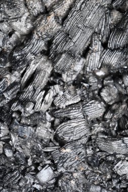 Mangal mangalına dönüşen kömür parçalarının siyah gri arka planına yumuşak bir odak. Tahta kömürlere ve kor dokusuna seçici odaklanma