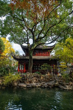 Göl kıyısındaki sonbahar ağaçlarının bahçesinde antik pagoda binası