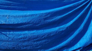 Buruşmuş plastik kumaş dokusu ve fotokopi alanı. Çapraz dalgalı yapısı olan eski mavi örtü arkaplanı