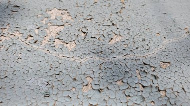 Eski beton duvarın yüzeyindeki uzun çatlaklı boyanın kirli dokusu haritadaki toprak yola benziyor. Dökülen boya tabakası yakın plan.