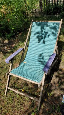 Çizgili hamağı ve yapraklı ağaç dallarının gölgeleriyle teras sandalyesi. Arka bahçe mobilyaları