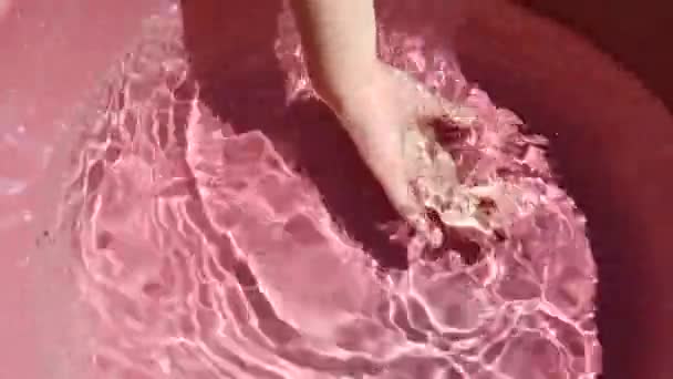Kind wäscht Hand in klarem Wasser in rosa Pool. Sommerwasser Spiel — Stockvideo
