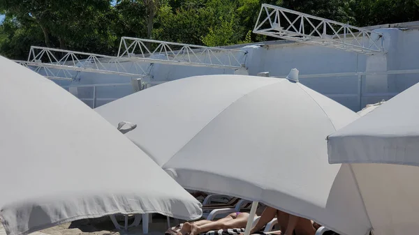 不认识的人在海滨的白色海滩遮阳伞下晒日光浴 欧洲海滩的日光浴 — 图库照片