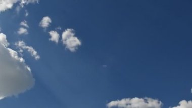Mavi gökyüzünde uçan beyaz kabarık bulutlar. Rüzgarlı yaz havasının zamanı