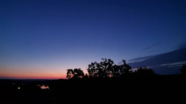 コピースペースと朝の青オレンジグラデーション色の空の背景に木のシルエットと素晴らしい日の出の風景 誰もいない静かな夜明けの風景 — ストック写真
