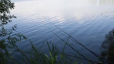 Gölün sakin su yüzeyindeki oltalar. Balıkçı yaşam tarzı konsepti. Nehirde balık avı sporu