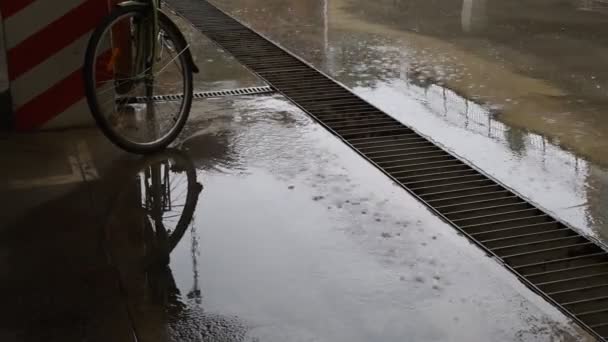 泥泞的水坑和雨滴滴滴在城市街道上的脏水表面 还有自行车停放 秋天的暴风雨天气 城市停车场水泥地面下细雨 自行车停放 — 图库视频影像