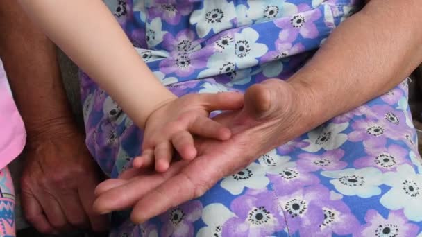 Las viejas manos arrugadas tocan y aplauden a los niños con manos suaves. Primeros planos de manos de nieto y abuela — Vídeos de Stock