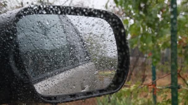 Vue floue du miroir latéral avec gouttes de pluie. Tir de l'intérieur de la voiture tandis que la bruine — Video