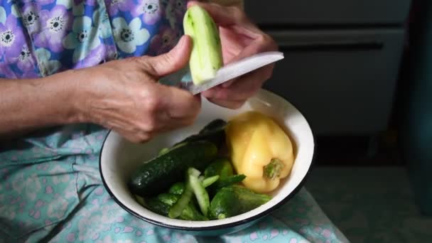 Stará žena loupe okurku s nožem v vrásčitých rukou — Stock video