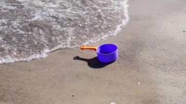 Güneşli yaz gününde, deniz suyunda ıslak kumsalda kayıp bir oyuncak.