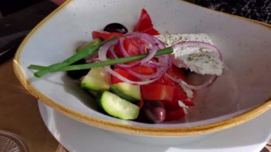 Elleri çatal ve bıçak kesme ve ev yapımı sebze salatası malzemelerini beyaz peynir ve yeşil soğanla birlikte alma. Yunanistan 'ın bölgesel yiyeceği. Sağlıklı yiyecekler yakın plan.