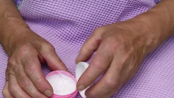 Η γριά απλώνει λευκή κρέμα ενυδάτωσης στο ρυτιδιασμένο χέρι της. Ηλικιωμένες γυναίκες — Αρχείο Βίντεο