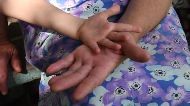Старша жінка зморшкував руки дотиком і рукою дитини. Крупним планом руки онука і бабусі — стокове відео