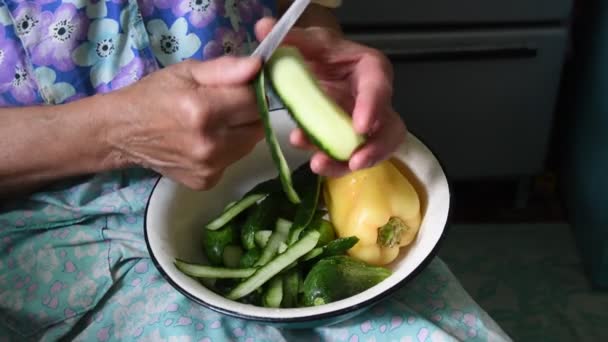 シニア女性皮キュウリでナイフで彼女のしわ手と2部に生野菜をカット — ストック動画