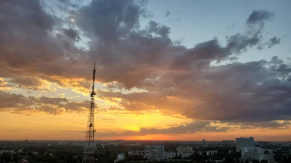 コミュニケーションタワーのシルエットで都市のスカイラインの上に息をのむ夕日 濃い青空のオレンジの雲背景 — ストック写真