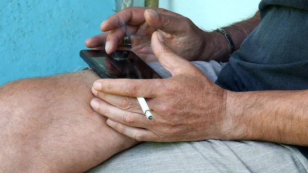 Азіатські Чоловічі Руки Тримають Сигарету Затискають Екран Смартфона Колінах Людина — стокове фото