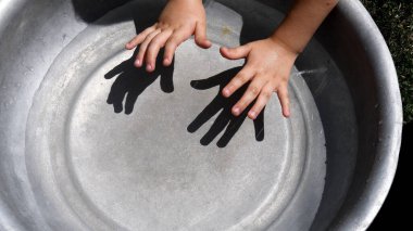 Parlak güneş ışığında temiz suda yıkanmadan önce çocuk elleri. Bebek elleri suyun üzerinde. Işık ve gölge