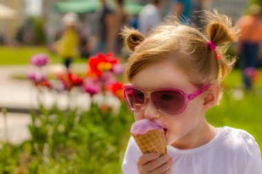 Kız moda gözlük dondurma yiyor. Çocuk ve lezzetli dondurma. Dondurmanın içine bulaşmış yüz
