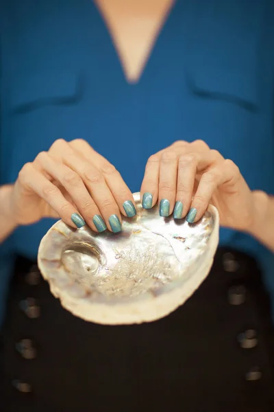 アワビの貝殻を持って完璧な青いマニキュアで美しい女性の手をバック グラウンドとして使用できます — ストック写真